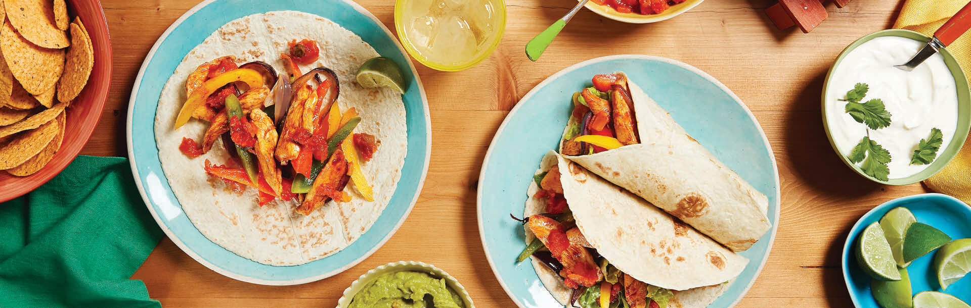 chicken fajitas served on a blue plate with guacamole, sour cream & diced lime on a wooden table