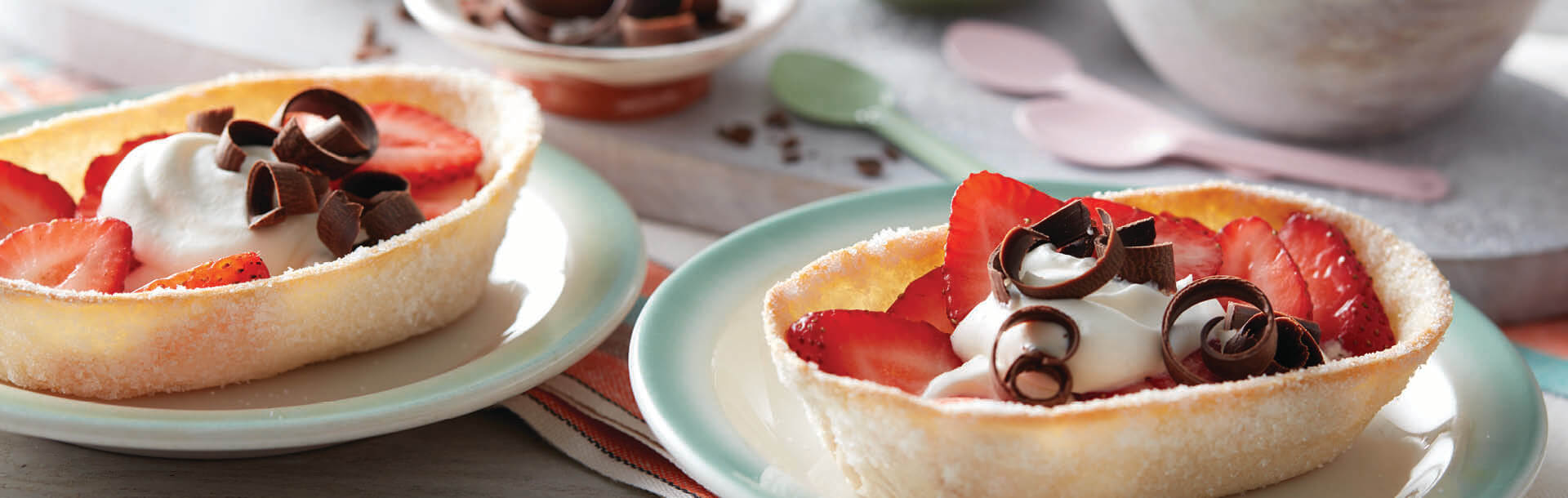 barchette di taco ripiene di fragole, panna e cioccolato grattugiato servite su un piatto